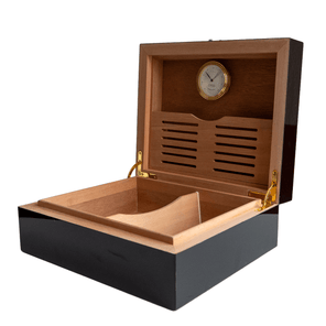 Interior de humidor negro con tapa abierta, incluye higrómetro dorado y compartimentos de madera.